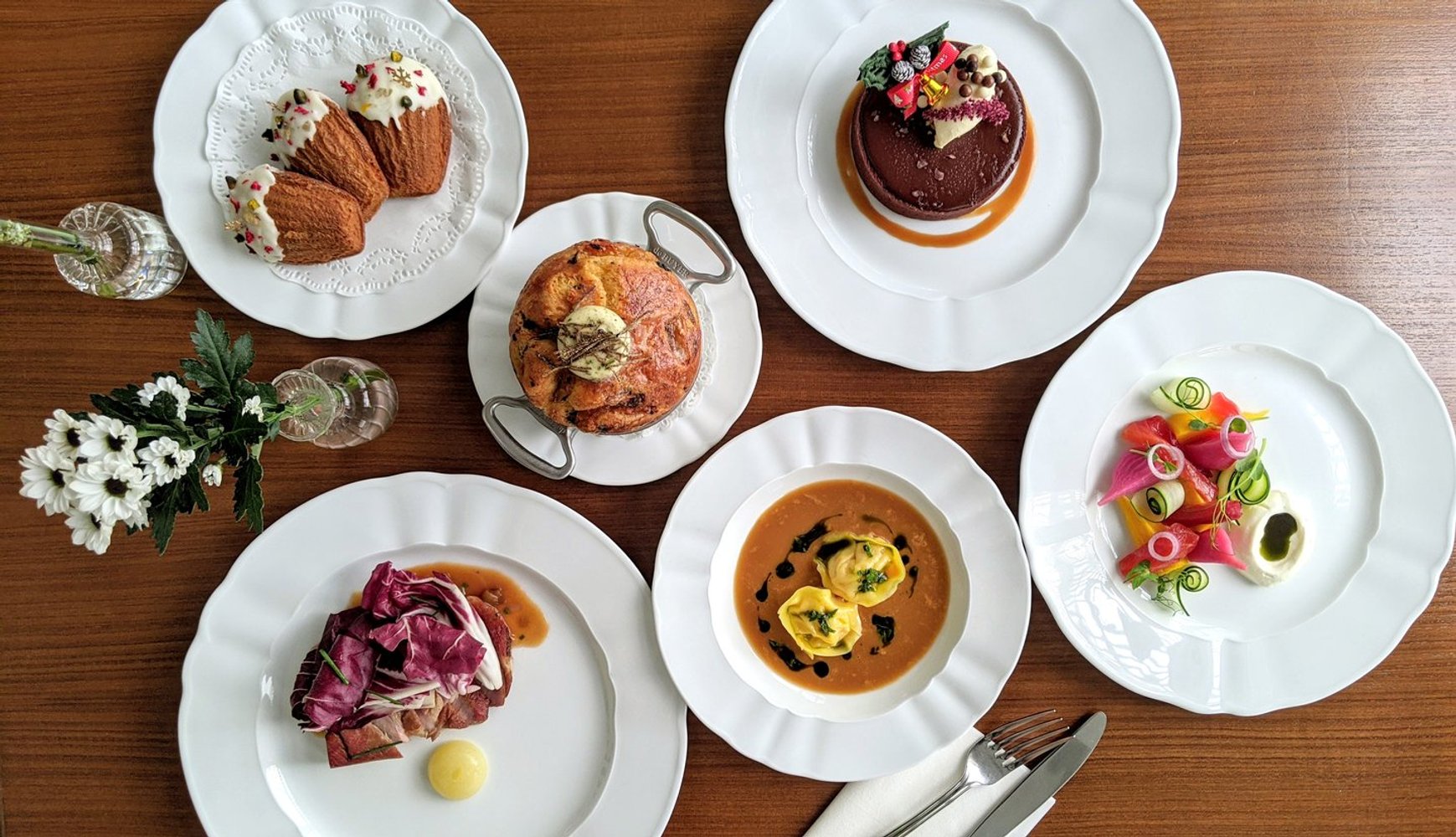 Six small plates of starters to dessert from The White Rabbit's Festive Indulgence Set for Christmas 2020. Includes a colourful salad, lobster bisque, Truffle and Brie Brioche, Beet-cured Salmon, Iberico Pork Collar Ham, glazed madeleines with colourful sprinkles, and a gleaming chocolate tart. 