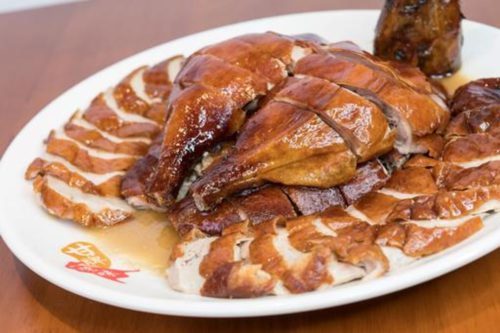 A plate of roast duck on a table. Whole Roast Duck from Kam's Roast, delivered islandwide in Singapore powered by Oddle